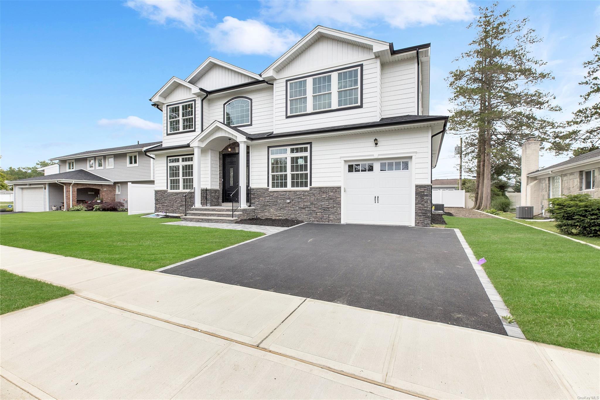 View of front of home with a garage, central AC, and a front lawn