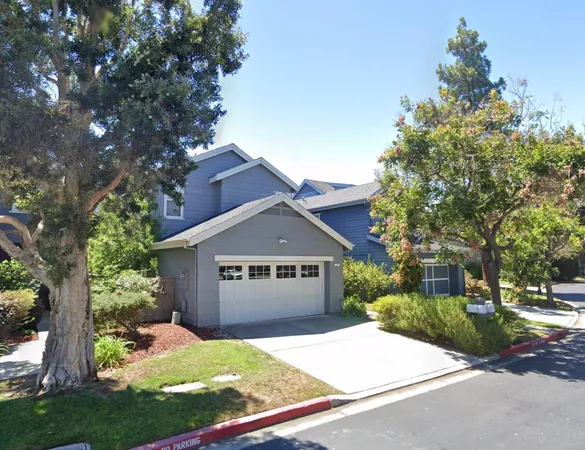 a front view of a house with a garden and trees