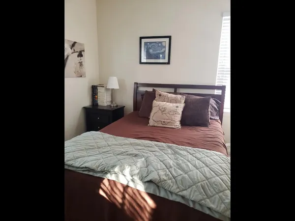 a bedroom with a bed and a lamp on dresser
