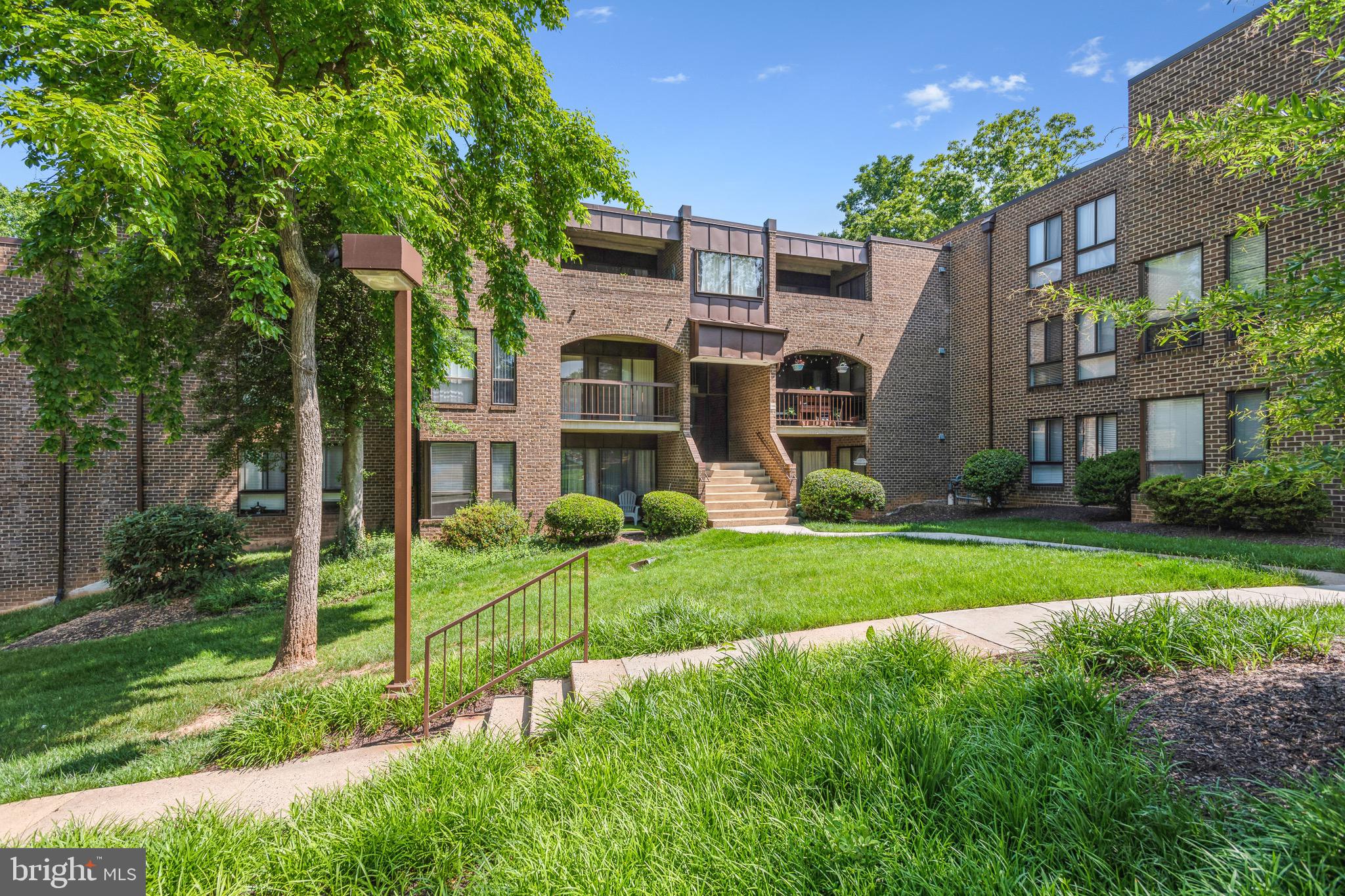 a view of a big yard in front of a brick house with large windows