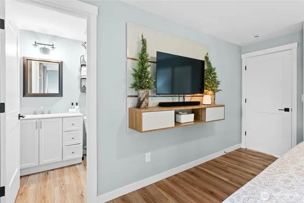 a bedroom with wooden floor and flat screen tv
