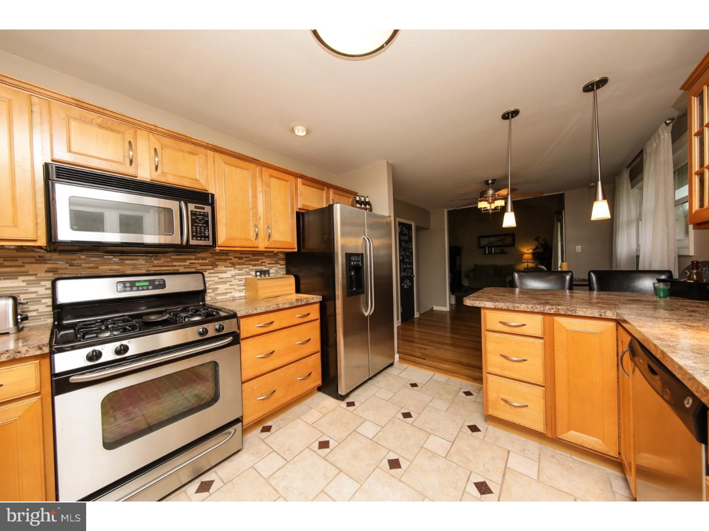 754 Spruce Road Warminster, PA 18974 - Photo 9 of 25 a kitchen with stainless steel appliances kitchen island granite countertop a stove a sink and a microwave