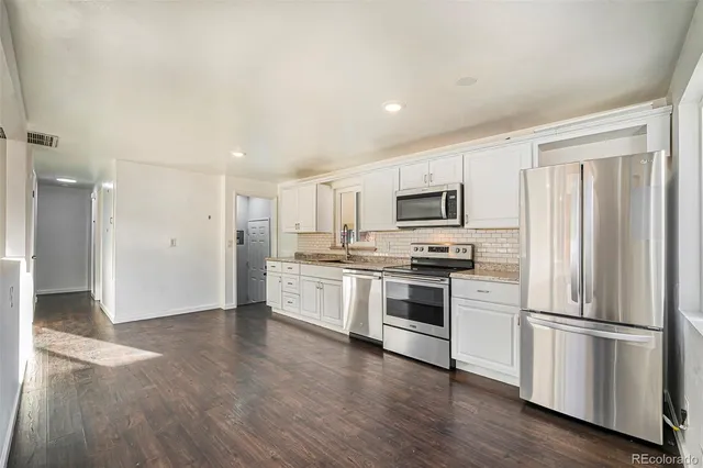 a kitchen with a refrigerator stove and wooden floor