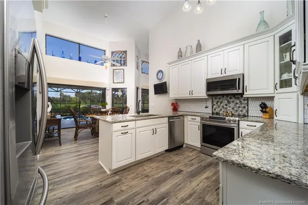 a kitchen with granite countertop a stove top oven a sink dishwasher and a refrigerator with wooden floor