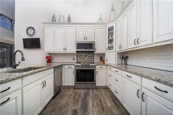 a kitchen with granite countertop white cabinets and white appliances