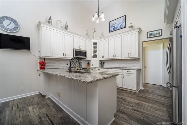 a kitchen with kitchen island granite countertop a sink cabinets and stainless steel appliances