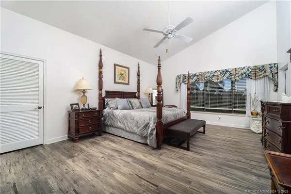 a spacious bedroom with a bed and wooden floor