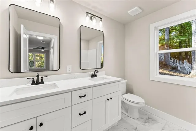 a bathroom with 2 sink toilet and a mirror