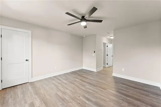 an empty room with wooden floor and a ceiling fan