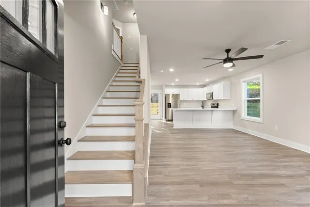 a view of an empty room with wooden floor and a ceiling fan