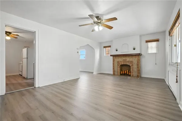 an empty room with wooden floor fireplace and windows