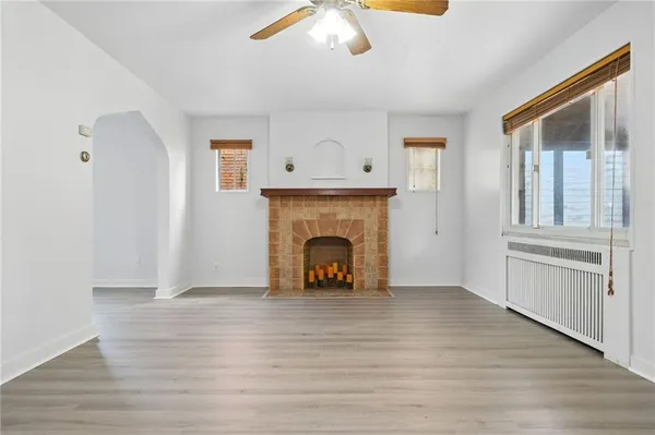 a view of an empty room with wooden floor fireplace and a window