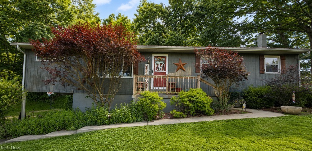 6700 McCaslin Road Nashport, OH 43830 - Photo 1 of 30 Gray-sided residence featuring a red entry door, a wooden porch, and a concrete walkway