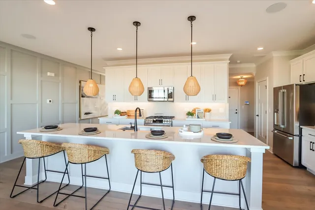 a kitchen with stainless steel appliances granite countertop a sink a stove a refrigerator with a dining table chairs and chairs