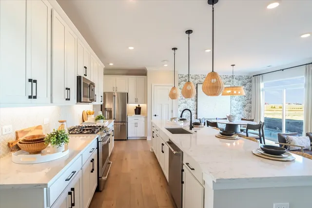 a kitchen with stainless steel appliances granite countertop a sink a stove and a wooden floor