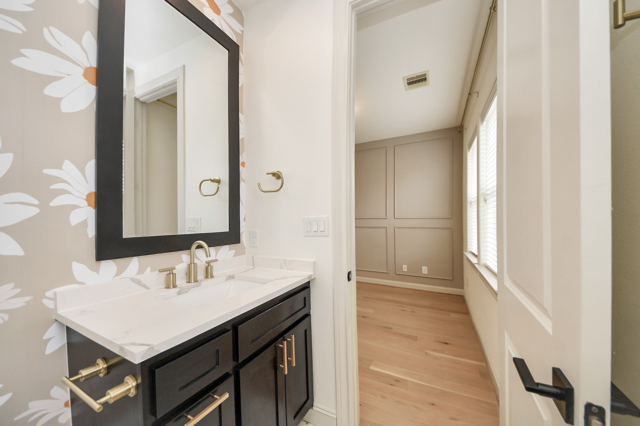 3229 Maxroy Street Houston, TX 77008 - Photo 39 of 43 A stylish en-suite bathroom for the third bedroom—located on the top level just down the hall from the primary suite—featuring a modern dark vanity, crisp white countertop, and unique accent wallpaper.