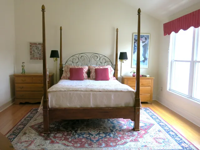 a bedroom with a bed a dresser next to a window