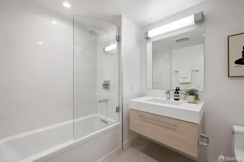 a bathroom with a sink a mirror a bathtub and shower