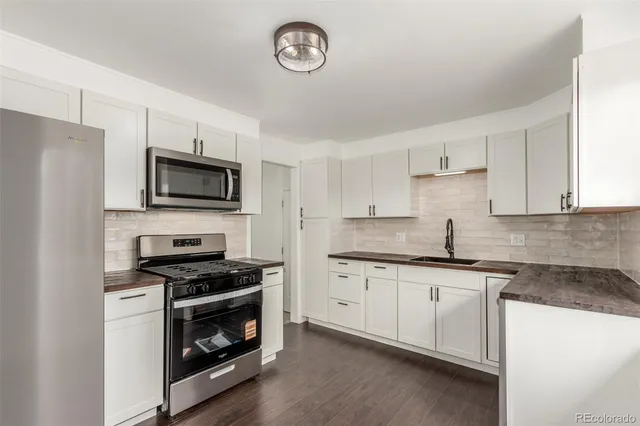 a kitchen with granite countertop a sink a stove a microwave and cabinets