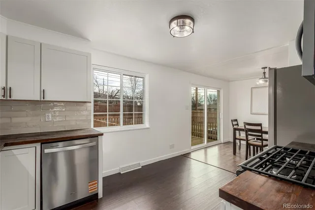 a kitchen with stainless steel appliances wooden floor dining table and chairs