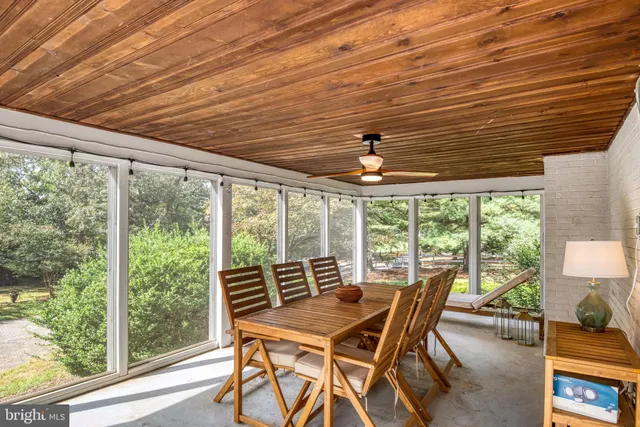 a dining room with furniture large windows and wooden floor