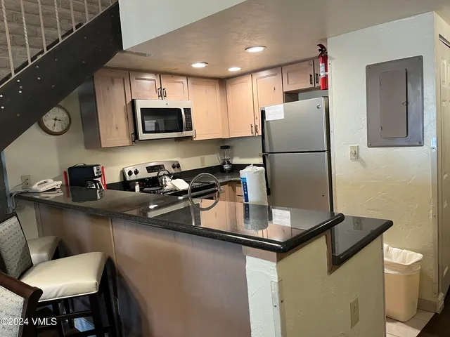 a kitchen with a sink a refrigerator and chairs