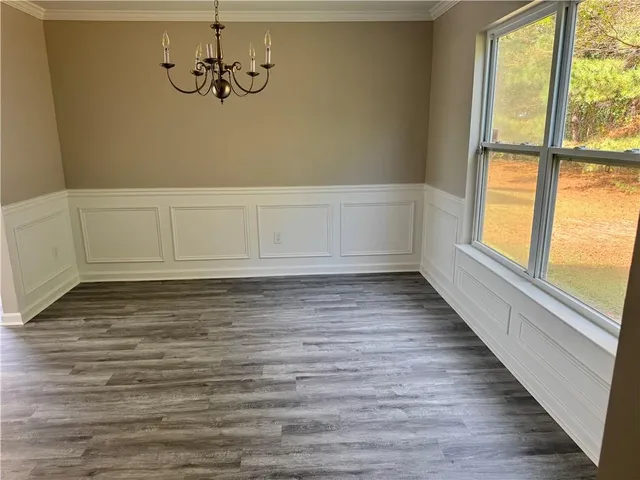 a view of an empty room with wooden floor and fan