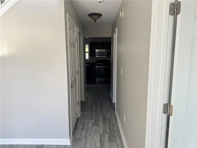 a view of a hallway with wooden floor and a bathroom