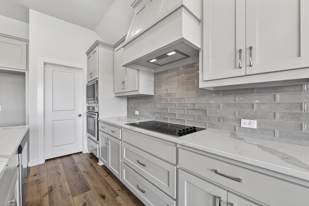 416 McAlpine Drive Springtown, TX 76082 - Photo 17 of 40 Contemporary kitchen featuring light gray cabinetry, built-in stainless steel appliances, a flush-mount cooktop, and a subway tile backsplash