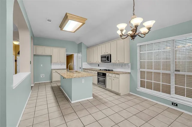 a kitchen with stainless steel appliances granite countertop a sink counter space cabinets and a view of living room