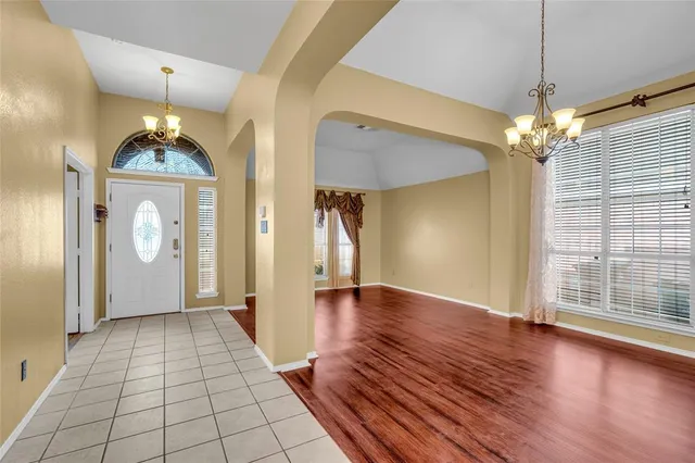 a view of a hallway with wooden floor and a chandelier
