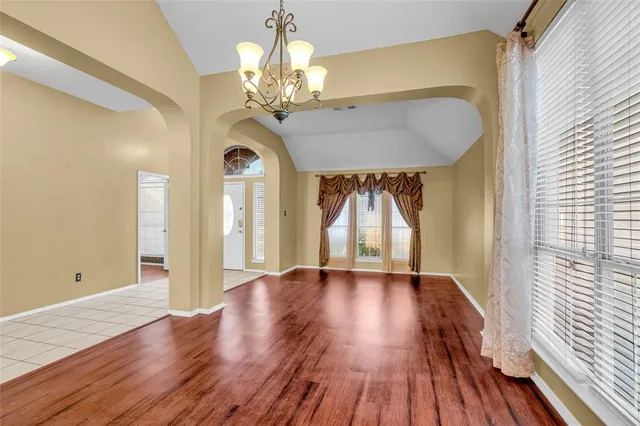 a view of a room with wooden floor chandelier and a window