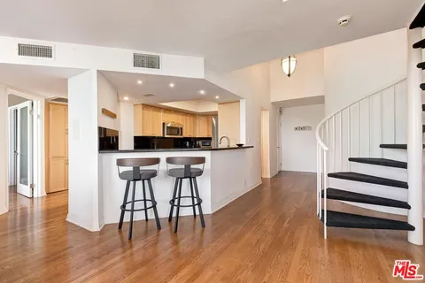 a kitchen with stainless steel appliances kitchen island granite countertop a table chairs and a refrigerator