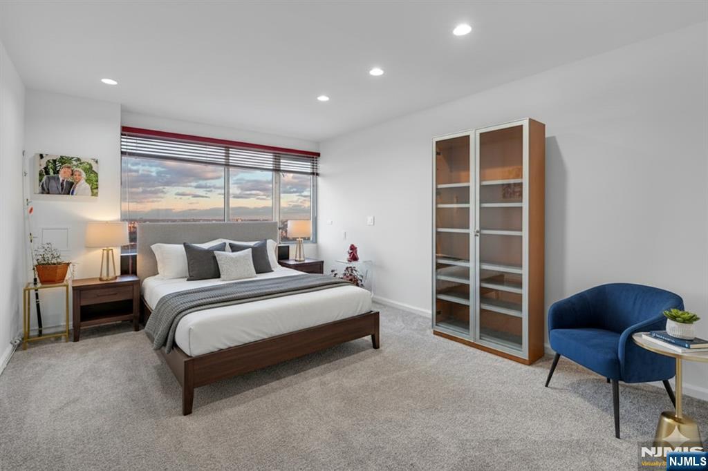 5 Horizon Road, Unit 2909 Fort Lee, NJ 07024 - Photo 17 of 29 a spacious bedroom with a bed and a chair