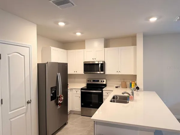 a kitchen with a refrigerator a stove top oven a sink and cabinets