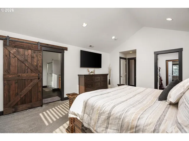 a bedroom with a large bed and a flat tv screen