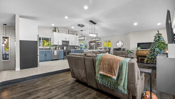 a living room with stainless steel appliances kitchen island granite countertop furniture wooden floor and a view of kitchen