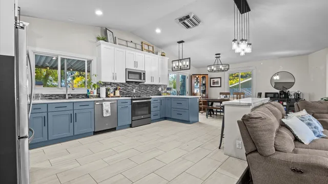 a kitchen with stainless steel appliances kitchen island granite countertop a stove top oven a sink a dining table and chairs with wooden floor