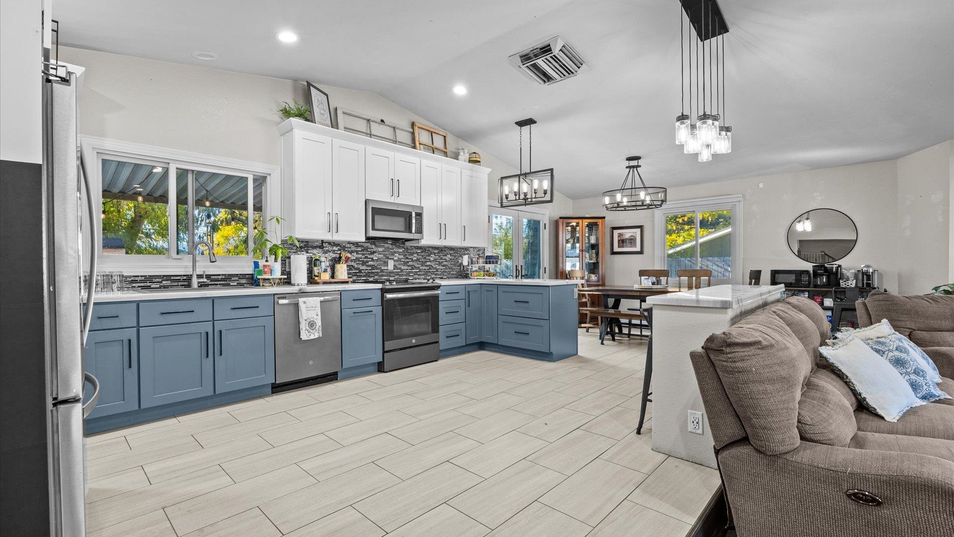 357 Music Lane Grand Junction, CO 81506 - Photo 10 of 29 a kitchen with stainless steel appliances kitchen island granite countertop a stove top oven a sink a dining table and chairs with wooden floor