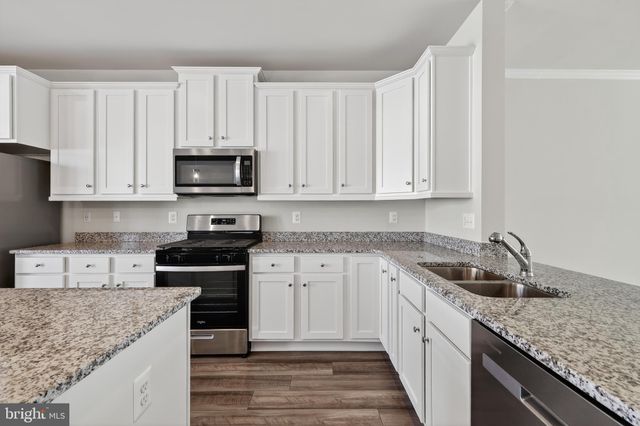 a kitchen with granite countertop white cabinets sink and stainless steel appliances