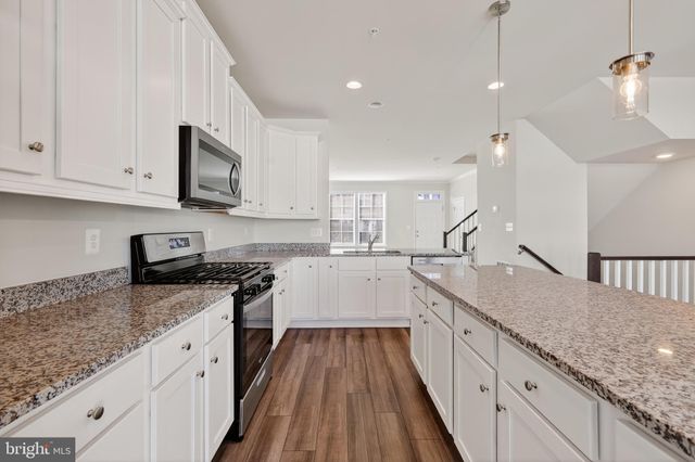 a large kitchen with stainless steel appliances granite countertop a stove sink and cabinets