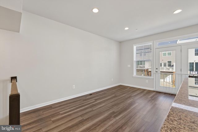 a view of empty room with wooden floor and kitchen