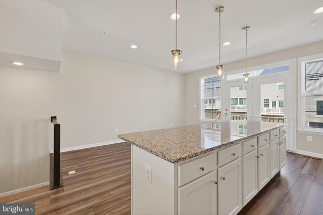 a kitchen with granite countertop white cabinets and chandelier