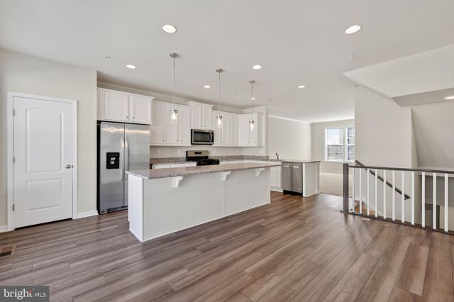 a kitchen with white cabinets stainless steel appliances and wooden floor