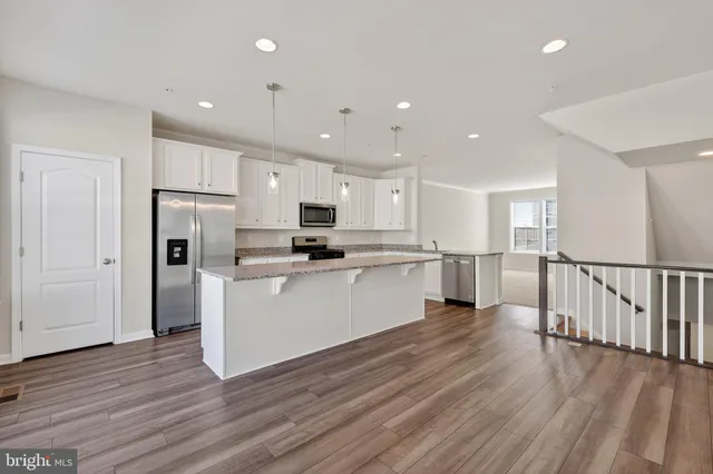 a kitchen with white cabinets stainless steel appliances and wooden floor