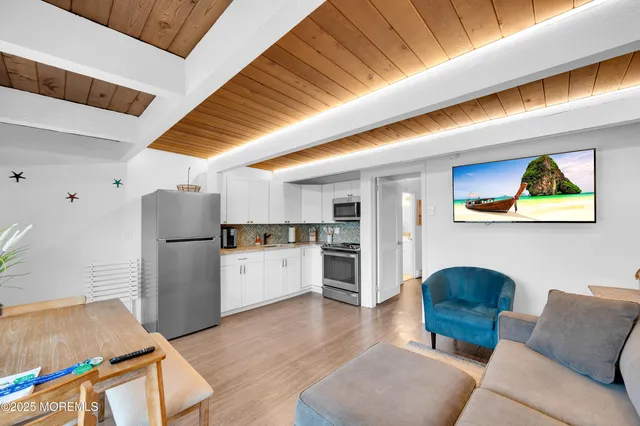 a living room with stainless steel appliances kitchen island granite countertop furniture and a refrigerator