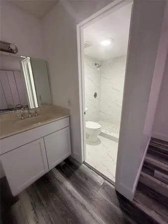 a bathroom with a granite countertop sink toilet and shower