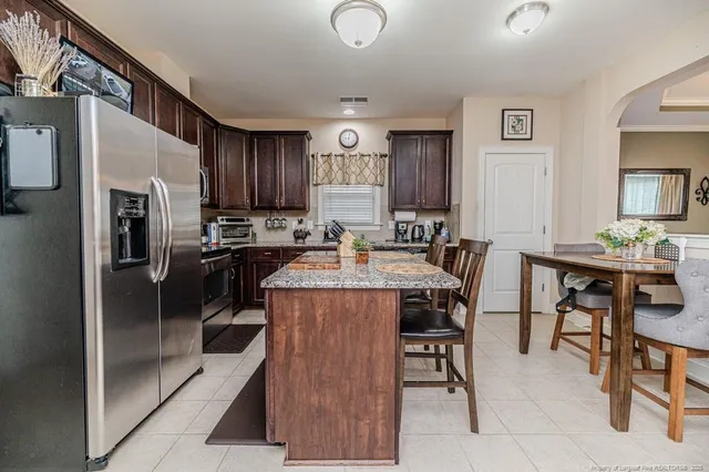 a kitchen with stainless steel appliances a table chairs refrigerator and cabinets
