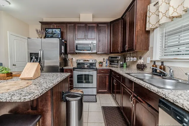 a kitchen with stainless steel appliances granite countertop a sink stove microwave and refrigerator