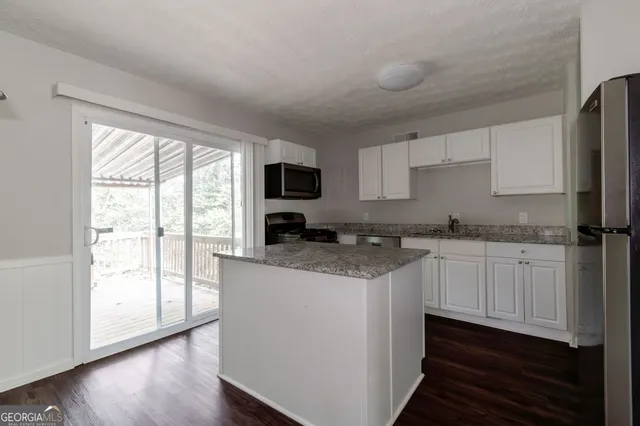 a kitchen with granite countertop white cabinets and white appliances